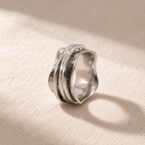 The Wave ring resting on natural linen